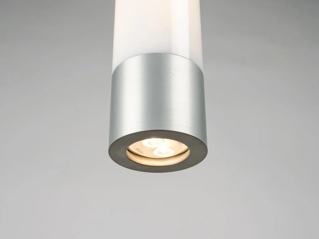 FUSE LED pendant light inspired by an automotive fuse, featuring a vertical illuminated form, acrylic cylindrical shade, and slim suspended cable for a floating appearance. Manufactured by Karice.