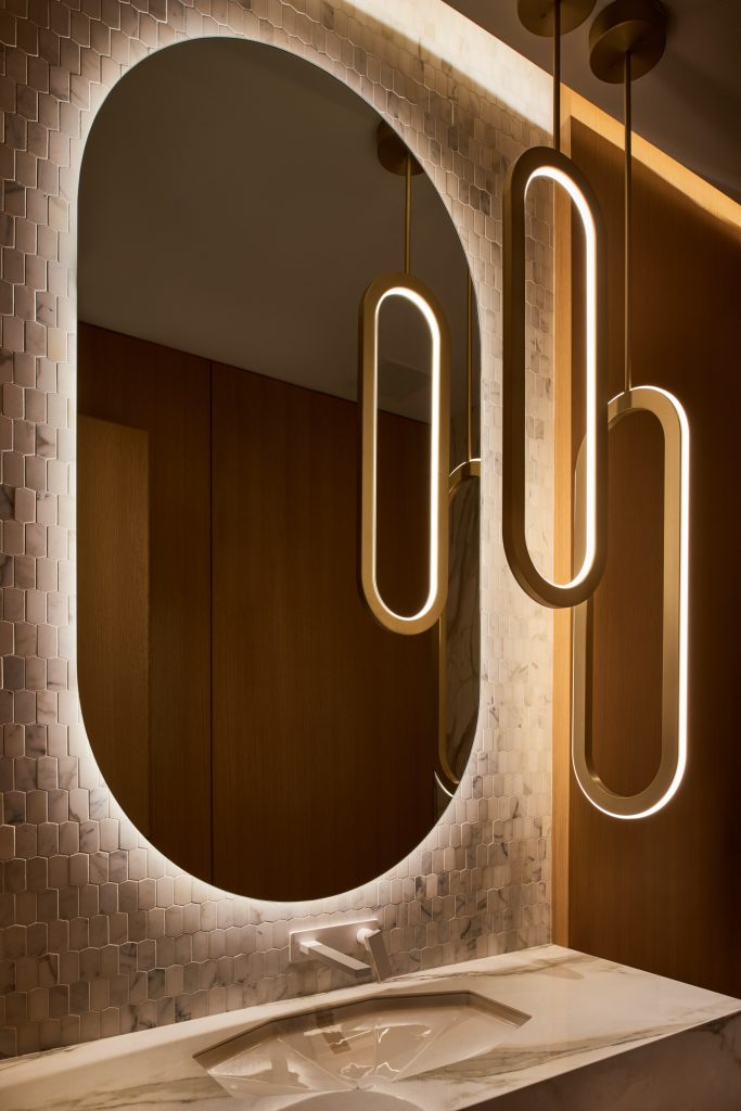 Elongated rounded-rectangle decorative pendant lighting in powder room of a private residence. Manufactured by Karice.
