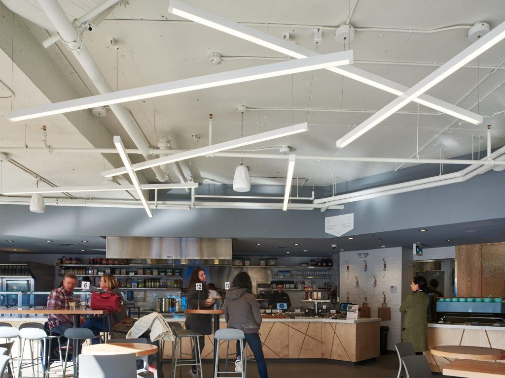 Linear pendant custom architectural lighting for Tractor Foods (Broadway). Manufactured and installed by Karice.
