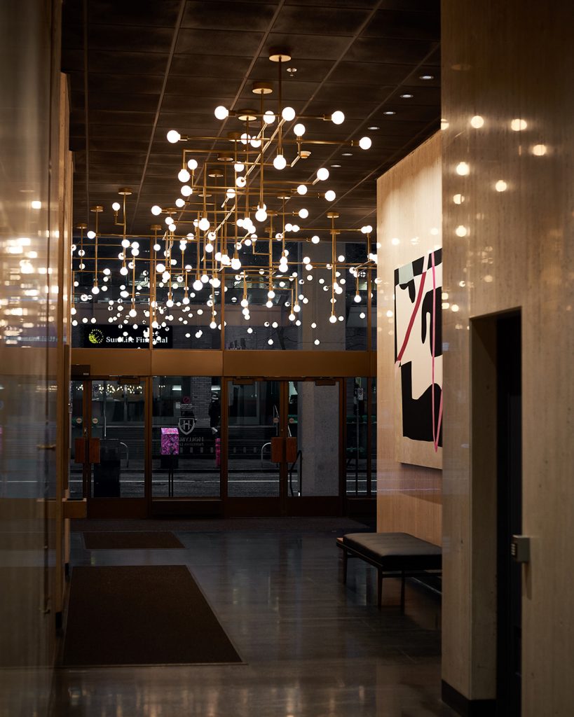 Custom multi-arm bulb chandeliers with brass finish for Hollyburn Properties in Vancouver, BC, CA. Manufactured by Karice.