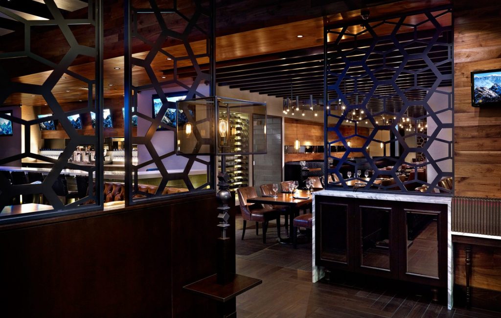 Custom wagon wheel chandeliers and glass-framed Edison bulb table lamps for Earls Kitchen and Bar in Cherry Creek, Denver, CO, USA. Manufactured by Karice.