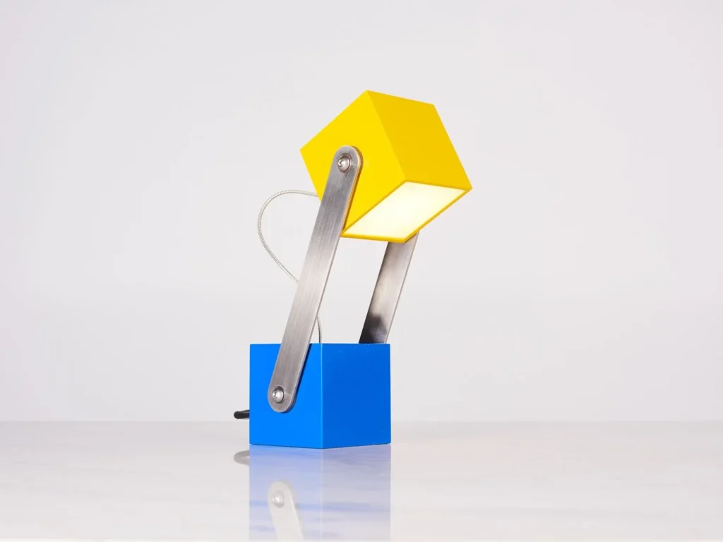 CUBE table lamp inspired by the Rubikโs Cube and Meccano sets, with an adjustable geometric design and multiple finish options. Designed and manufactured by Karice.