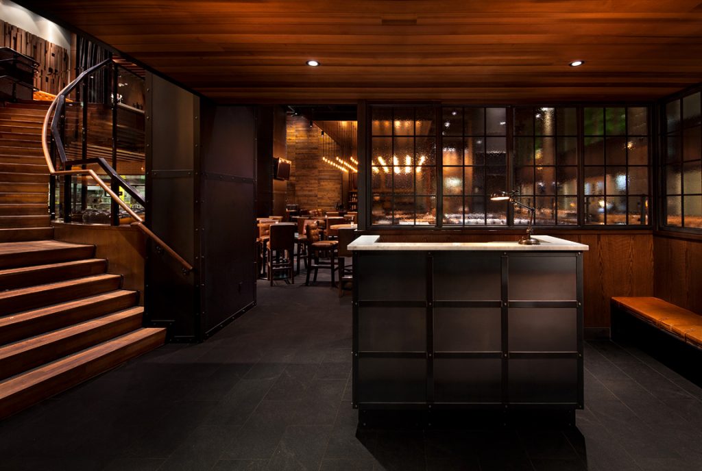 Custom multi-pendant filament bulb chandelier and lobby area metalwork for Earls Kitchen & Bar in Hornby Street, Vancouver, BC, CA. Manufactured by Karice.