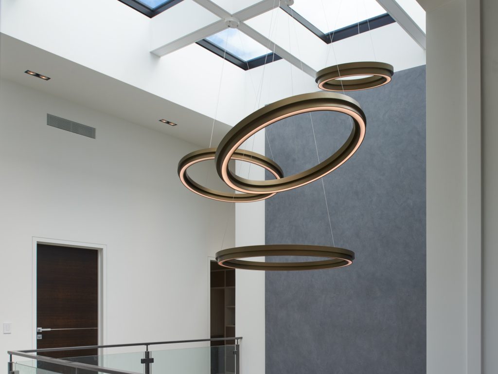 Clustered circular ring pendants in front entry a private residence. Manufactured by Karice.