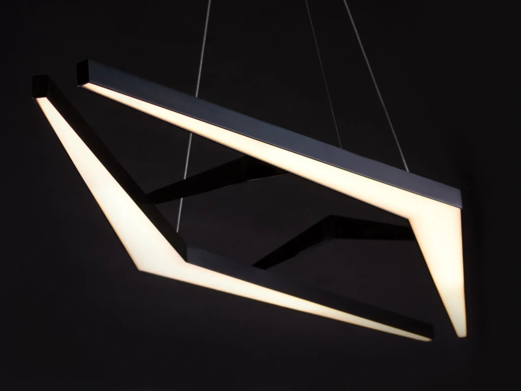 AREA 49 geometric luminaire with double-chevron form, aluminum construction, and powder-coated finish. Designed and manufactured by Karice.