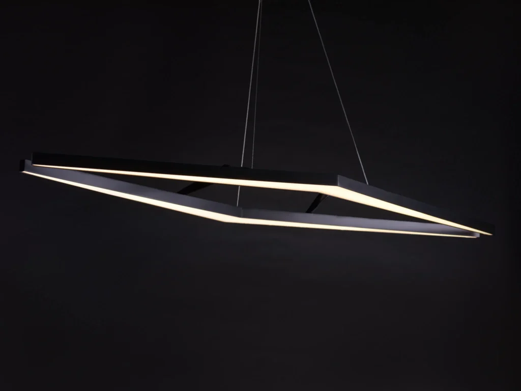 AREA 49 geometric luminaire with double-chevron form, aluminum construction, and powder-coated finish. Designed and manufactured by Karice.