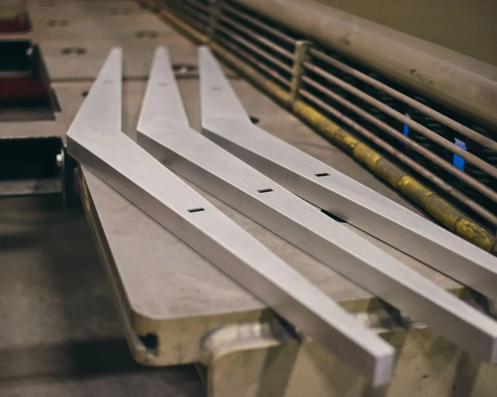AREA 49 geometric luminaire with double-chevron form, aluminum construction, and powder-coated finish. Designed and manufactured by Karice.