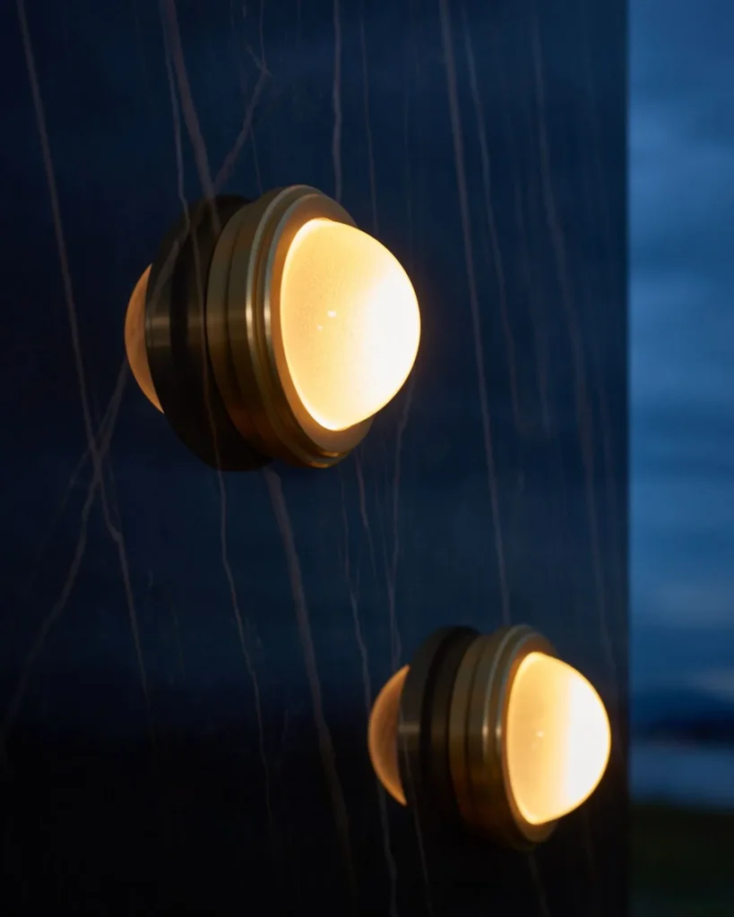 Infinity wall sconce with anodized aluminum, magnifying glass domes, concealed mounting plate, and adjustable illumination. Designed and manufactured by Karice.