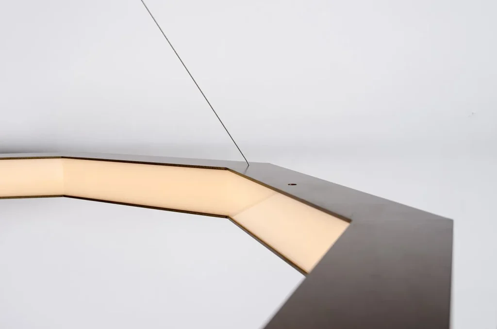 Luxennea enneagon LED pendant with aluminum frame, acrylic diffuser, and custom bronze finish. Designed and manufactured by Karice.
