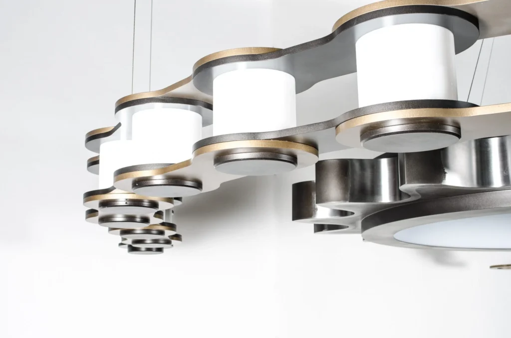 The Sprocket and Chain 10-foot LED chandelier features an oversized gear-and-chain form, suspended by concealed aircraft cables and fasteners. Designed and manufactured by Karice.